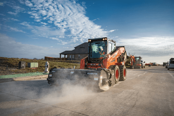 Skid steer cleaning debris on a construction site